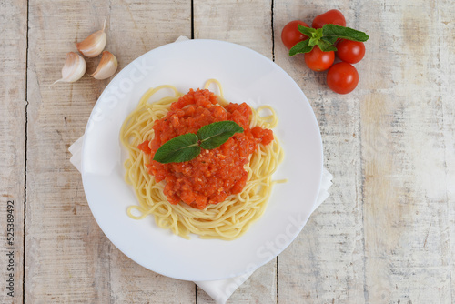 Top view of plate with spaghetti in tomato sauce and basil. Copy space for text