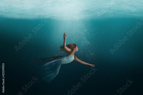 Girl floating underwater in a surreal dreamlike state