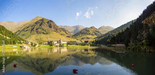 Panoramic of Vall de Núria's lake with the resort and the mountains in the background. Summer outdoor activities like hiking, canoes and boats. Beautiful sunny landscape. photo