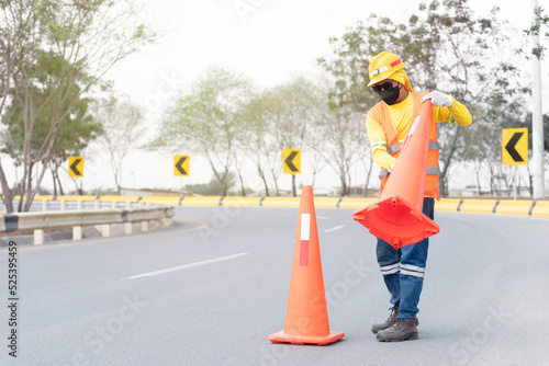 Construction worker putting traffic cones on the highway. Workwear, copy space.