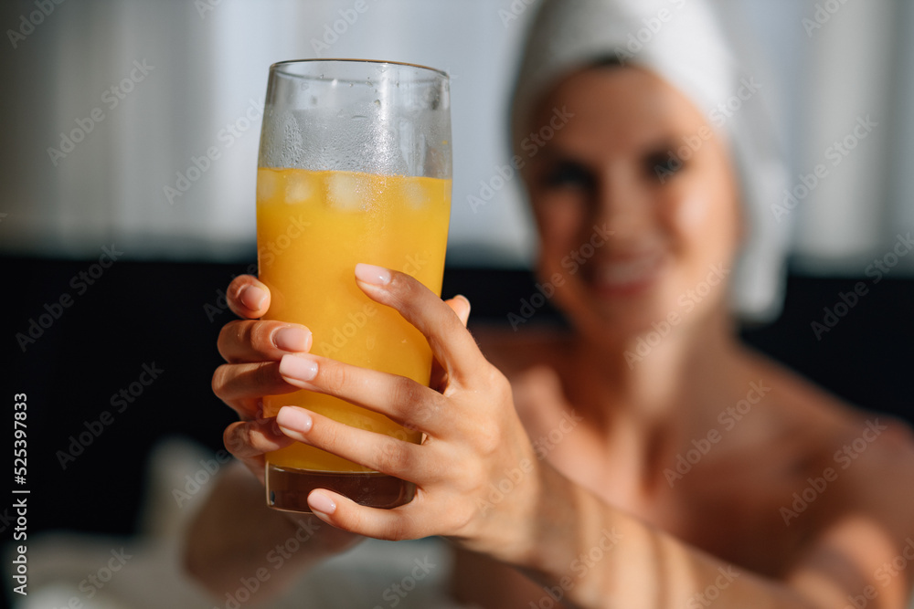 Young woman having breakfast in a modern hotel apartment. Window light portrait of a young girl in a bathrobe lying on the bed using a laptop for work. Out of focus tray with food, juice. Freelancer Young woman having breakfast in a modern hotel apartment. Window light portrait of a young girl in a bathrobe lying on the bed using a laptop for work. Out of focus tray with food, juice. Freelancer