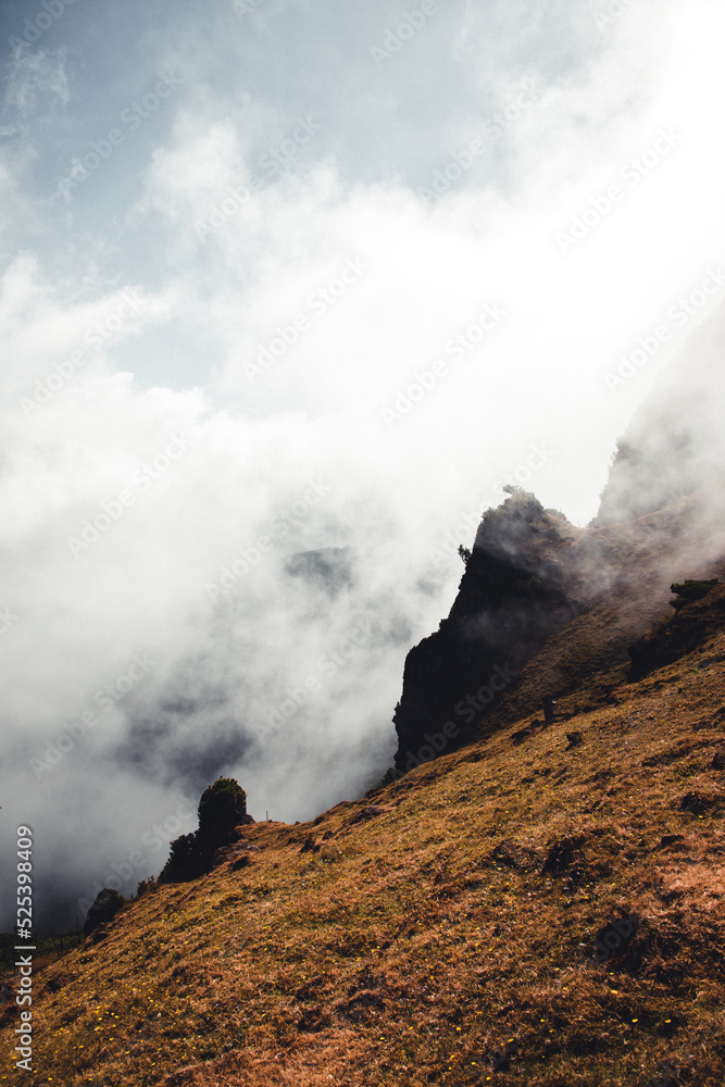 Mist and fog rising over mountains on Madeira, with dry meadows in the foreground