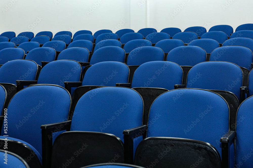 Naklejka premium Rows of several blue chairs in an auditorium, or theater, with no person and all seats the same.
