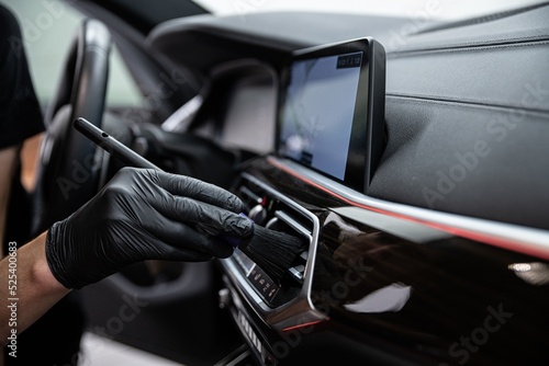 car detailing studio employee carefully cleans the air vents with a brush