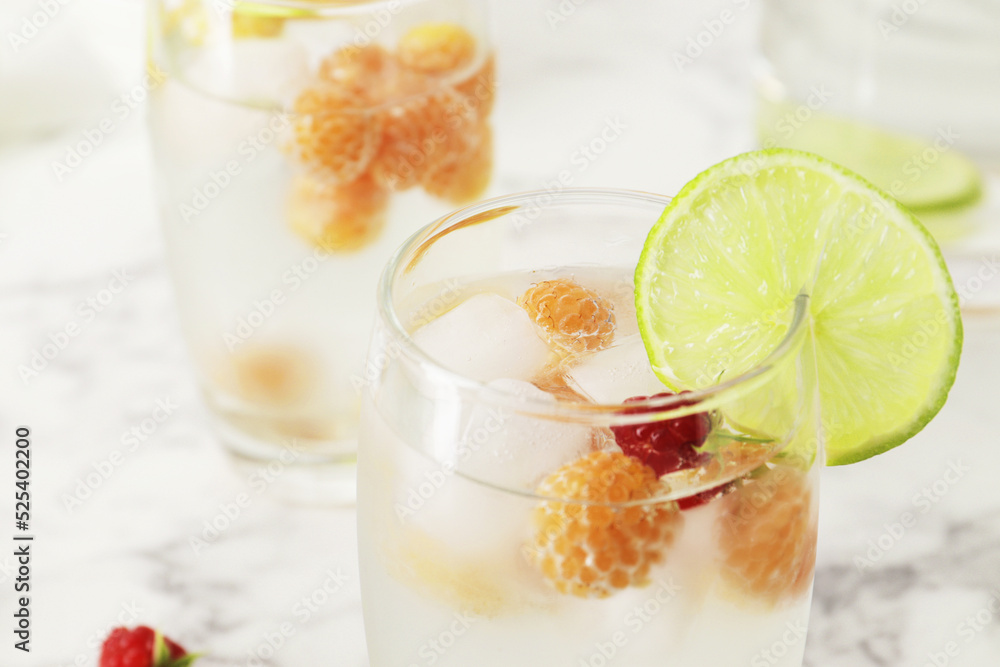 Glass and jug with fresh water and lime on marble table. Space for text. Flavored water. Summer drinks. Raspberry, mint and lime. Glass and jug with fresh water and lime on marble table. Space for text. Flavored water. Summer drinks. Raspberry, mint and lime.
