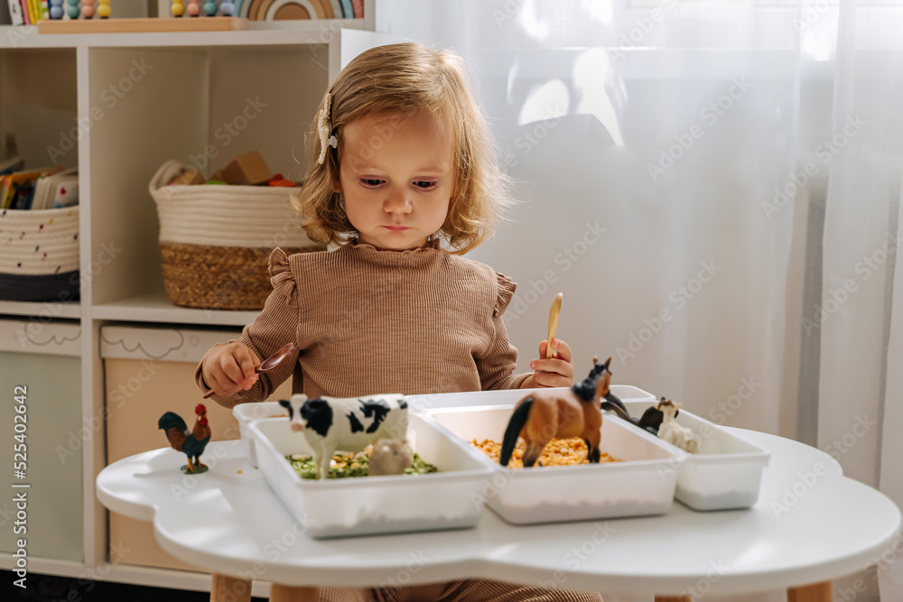 A Little Girl Playing With Farm Animals In Sensory Bin In Nursery