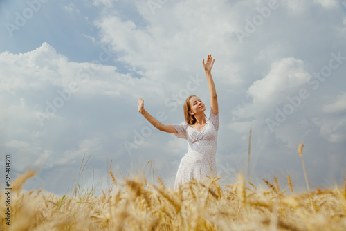 Young woman in summer dress dancing alone in ripe wheat field