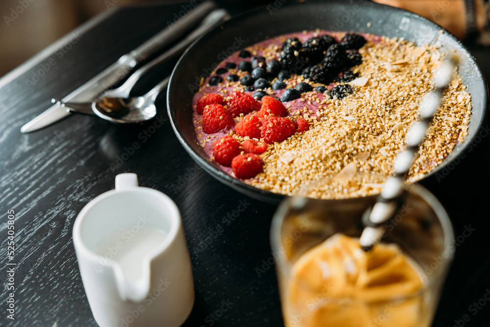 Shallow focus on a bowl of oatmeal, yogurt and fruit with an iced coffee in foreground Shallow focus on a bowl of oatmeal, yogurt and fruit with an iced coffee in foreground