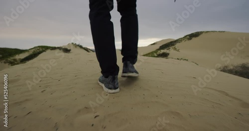 Man walks on sand dunes with camera at Oceano Dunes SVRA at Pismo Beach, California photo