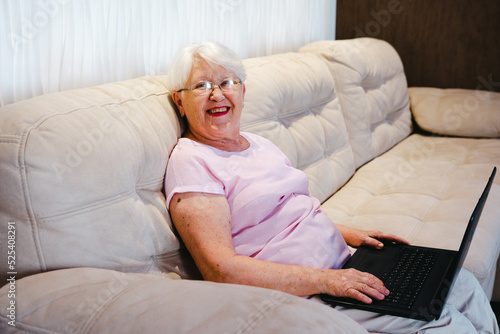 happy elderly woman using laptop computer at home. Senior mature older woman watching business training, online webinar on laptop computer remote working or social distance learning from home. 60s 