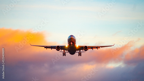 The silhouette of a passenger plane coming in for landing against the backdrop of the sunset sky.
