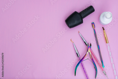 Fototapeta Naklejka Na Ścianę i Meble -  basic elements for a manicure, placed on a pink background. black and white nail polish, colored brushes, cuticle pusher and cuticle nippers items for sale and marketing in the aesthetic beauty market