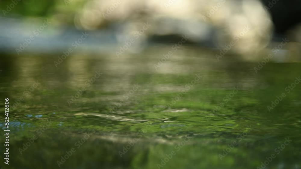 Green water in a natural pool of a mountain river with burry stones in the background (slow motion, bokeh) Green water in a natural pool of a mountain river with burry stones in the background (slow motion, bokeh)