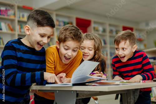 school children in the library reading books, doing homework, prepare a school project for lessons