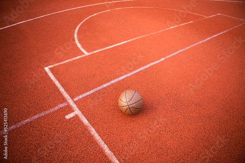 Top view orange ball for basketball lying on the rubber sport court. Sport red ground outdoor in the yard. 