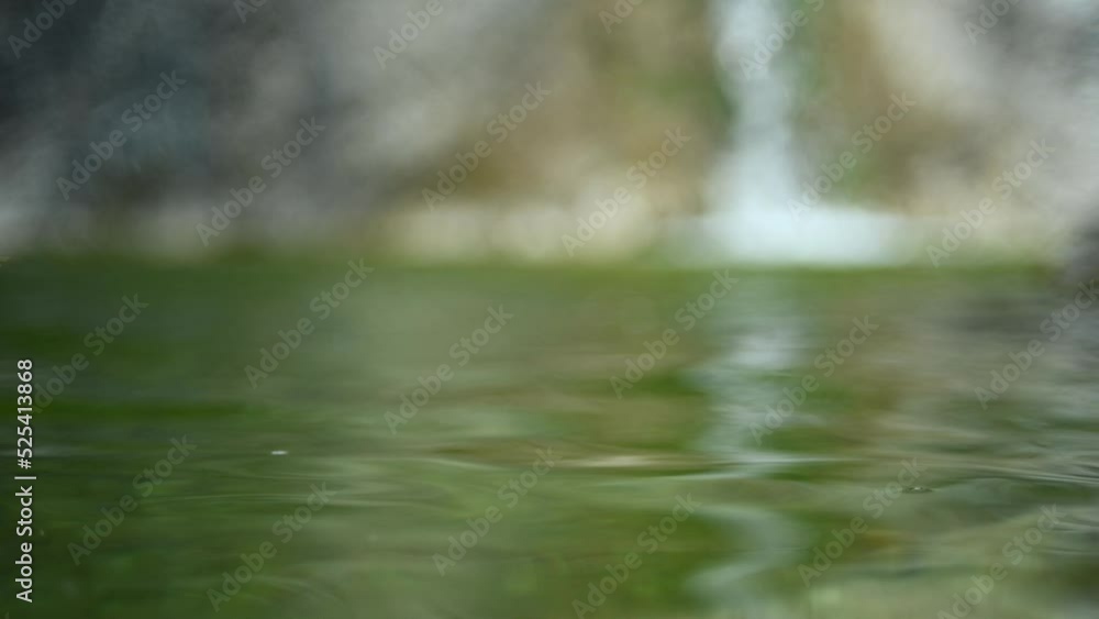 Waves in a natural pool with green water and a waterfall in the blurry background (boken, slow motion) Waves in a natural pool with green water and a waterfall in the blurry background (boken, slow motion)
