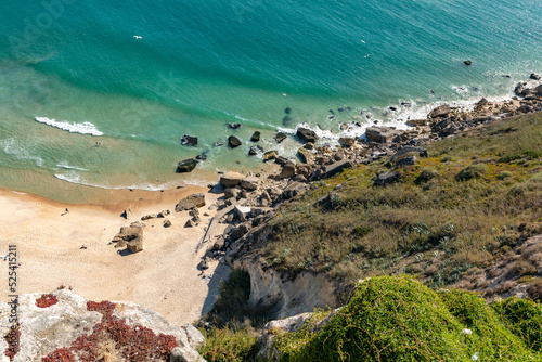 Rocks and sandy beach on the cliffs of the tourist resort of Nazare on the Atlantic coast of Portugal photo