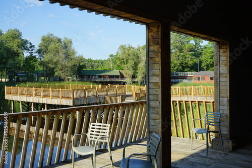 Veranda mit Schiffsdielen aus Holz und Stühlen in grüner Auenlandschaft im Sommer vor blauem Himmel im Sonnenschein im Acarlar Auenwald bei Karasu in der Provinz Sakarya in der Türkei photo