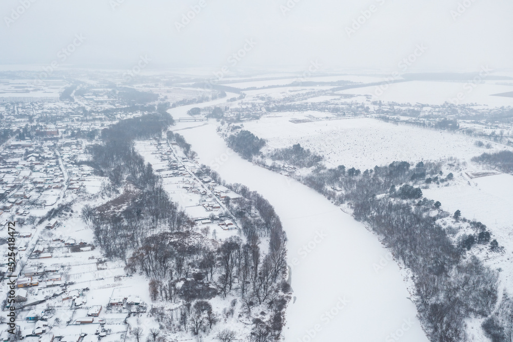 Aerial view of a frozen river. The river is frozen and covered with snow, severe frosts