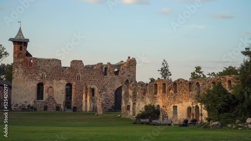 The landscape of Dobele castle ruins (Latvia) in the evening light at sunset time. The medieval stone walls with the central building panoramic view after restoration and rebuilding work. photo