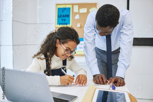Foto Portrait of smiling African American girl working with teacher in school classro