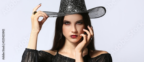 Obraz na plátně Beautiful woman dressed as witch for Halloween on light background
