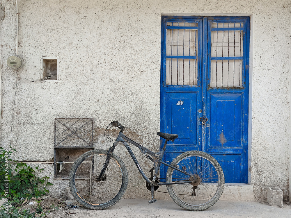 A bicycle parked in front of a worn blue door