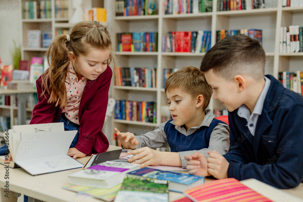 school children in the library reading books, doing homework, prepare a school project for lessons school children in the library reading books, doing homework, prepare a school project for lessons