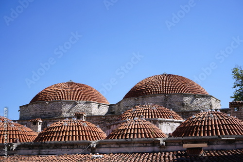 Altes Mauerwerk und Kuppeln des Tarihi Cinci Hamam vor blauem Himmel im Sonnenschein in der Altstadt des Unesco Weltkulturerbe Safranbolu in der Provinz Karabük in der Türkei photo