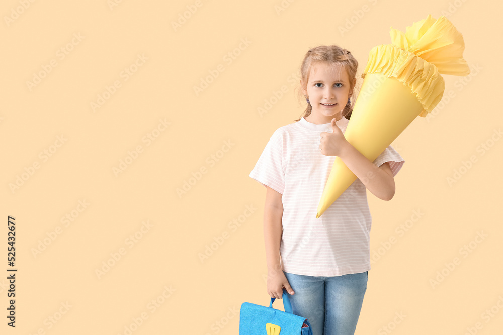 Cute little girl with yellow school cone and backpack on beige background Cute little girl with yellow school cone and backpack on beige background