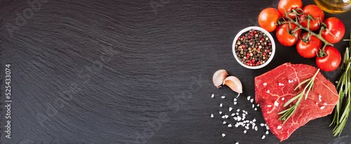 Panel kuchenny z motywem Raw beef steak with spices and ingredients for cooking on black slate background. Banner for restaurant menu, header for web sites. Top view, flat lay, mockup with copy space for text