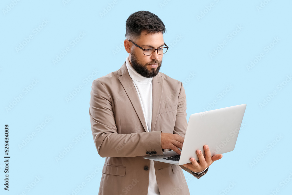 Handsome teacher of computer sciences using laptop on blue background Handsome teacher of computer sciences using laptop on blue background