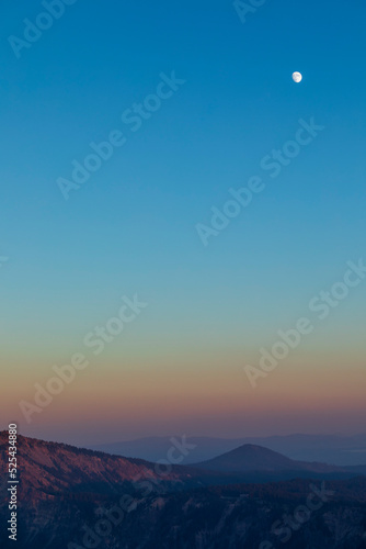 dramatic sunset sky on Crater Lake National park in Oregon with silhouette of surrounding mountain peaks on the background.