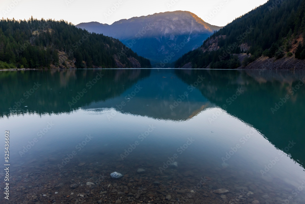 sunrise in still turquoise water of Thunder Arm in Diablo lake in Colonial Creek Campground in North Cascade National park, Washington