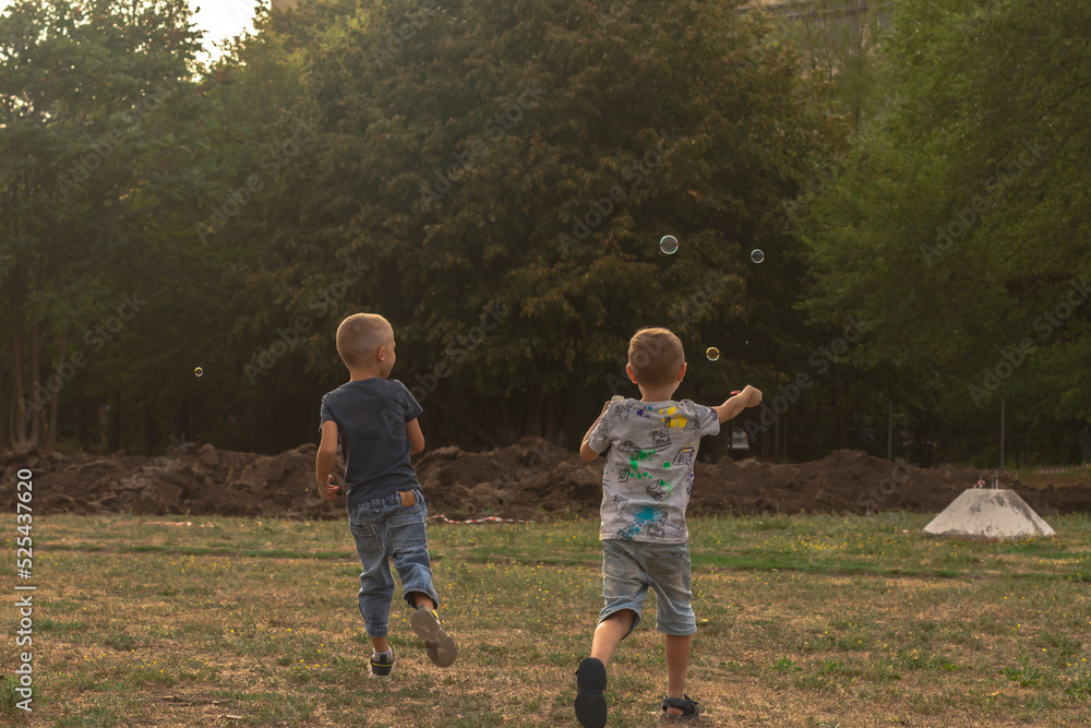Fototapeta premium Two boys playing with colorful soap bubbles