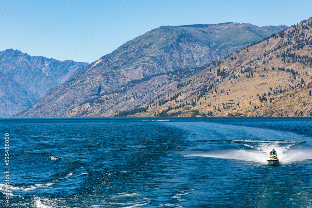 jet skiing in the blue colored Chelan Lake in Washington State during summer.