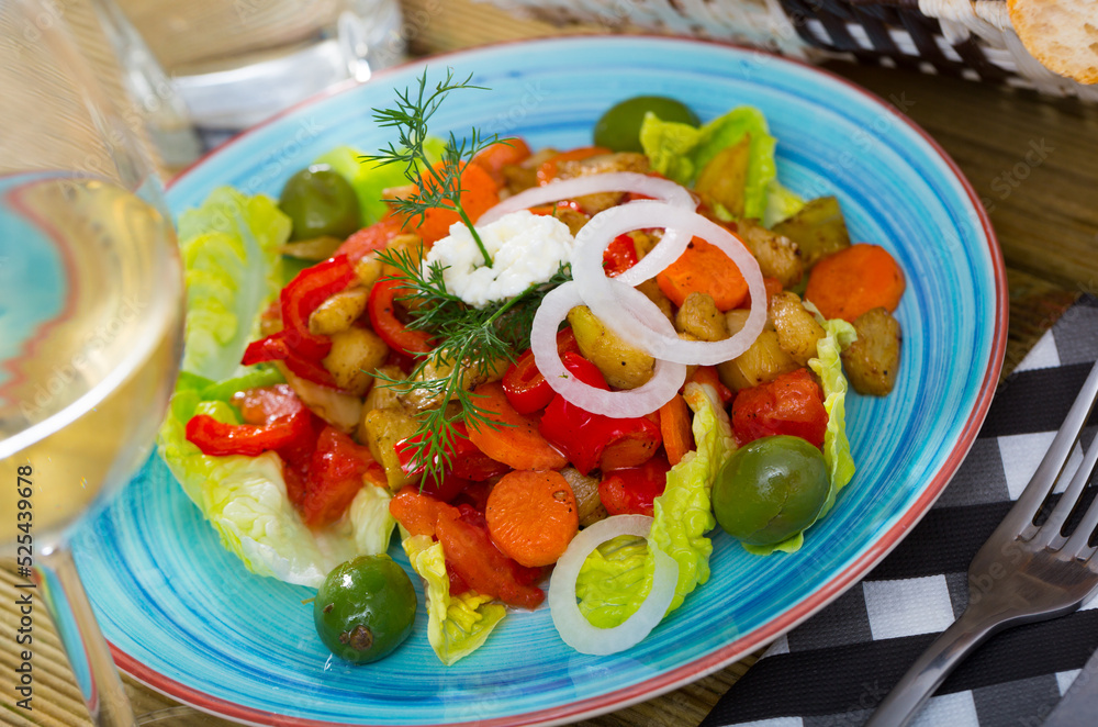 Delicious salad of baked vegetables garnished with olives, soft cheese and fresh dill