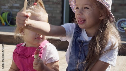 Two Sisters Children enjoys delicious ice cream cone. Child eating watermelon popsicle. Kids Siblings snack sweets in Home Garden. Summer holiday Hot weather Sunny Day. Childhood, Food Candy Friends.