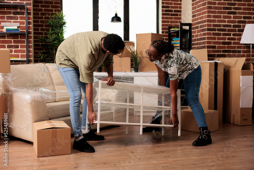 Foto Married people unpacking furniture to move in rented apartment flat together, enjoying household relocation