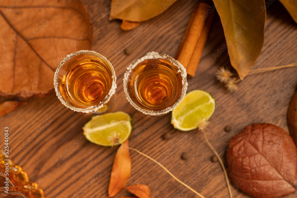 Tequila, shots with autumn decoration, with dry leaves on wooden table