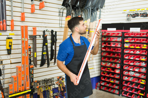 Obraz na plátně Caucasian male worker showing a level tool at the hardware store