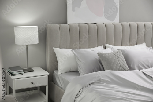 Foto Cozy bed with soft silky bedclothes in light room