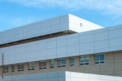 The exterior wall of a contemporary commercial style building with aluminum metal composite panels and glass windows. The futuristic building has engineered diagonal cladding steel frame panels.