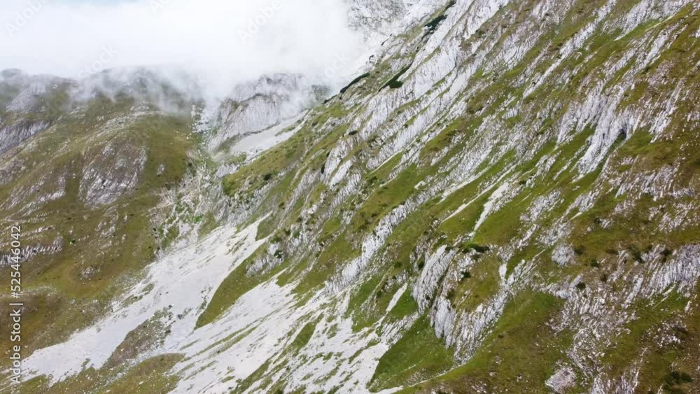 Aerial drone view of mountain in fog. Cloudy day in mountains. Cliffs and rocks at the top of mountain range. Clouds cross a mountain pass.
Aerial drone view of mountain in fog. Cloudy day in mountains. Cliffs and rocks at the top of mountain range. Clouds cross a mountain pass.