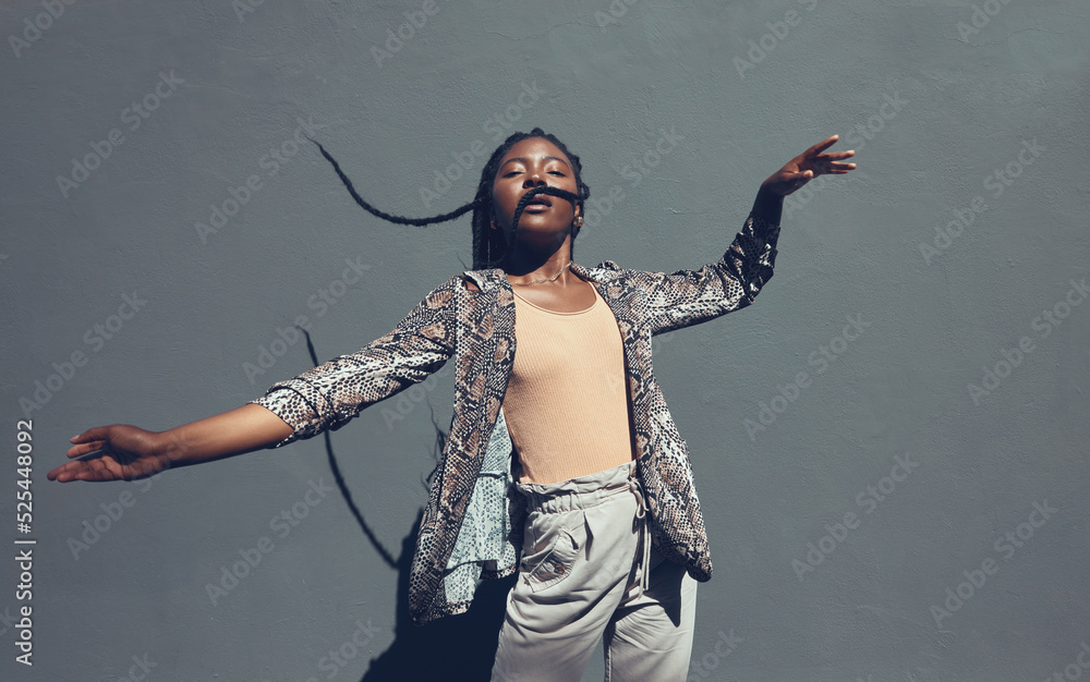 Fashion, style and trendy black woman against a gray background wall in a city, town and downtown. Street beauty model with funky, cool and hipster hair in edgy motion or movement expression outdoors