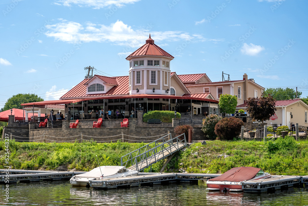 Obraz premium Schenectady, NY – USA - Aug 5, 2022 Waterfront view of the The Water’s Edge Lighthouse Restaurant, a 19th-century farmhouse turned into an American eatery with a cabana bar set along the Mohawk River.