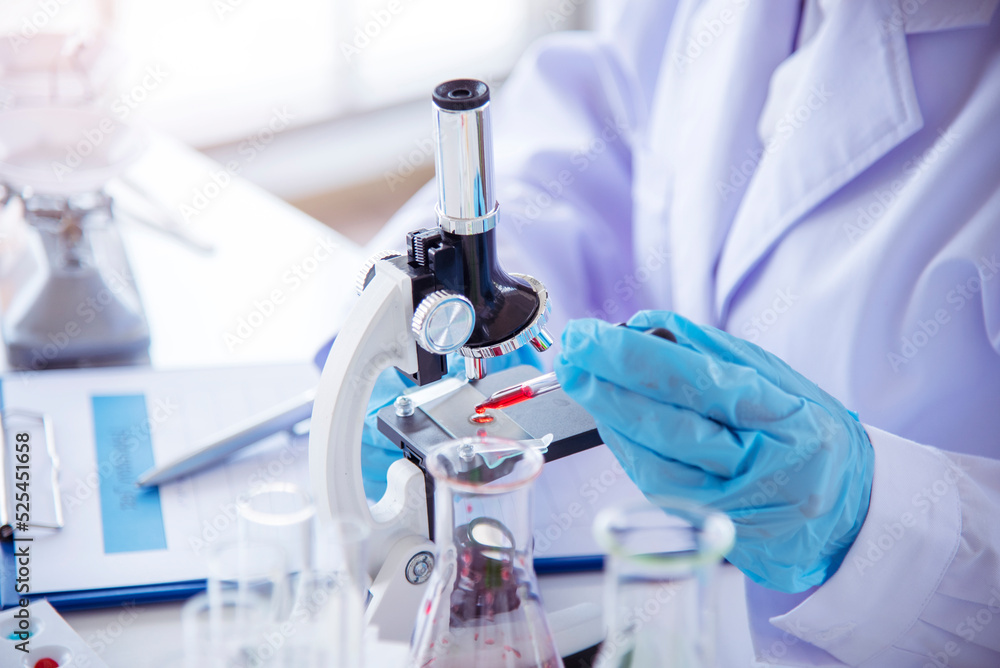 Woman scientist hand write note information in medical lab look at science microscope medical test, research biology chemistry. Asian Females technician laboratory analyzing blood test pharmaceutical Woman scientist hand write note information in medical lab look at science microscope medical test, research biology chemistry. Asian Females technician laboratory analyzing blood test pharmaceutical