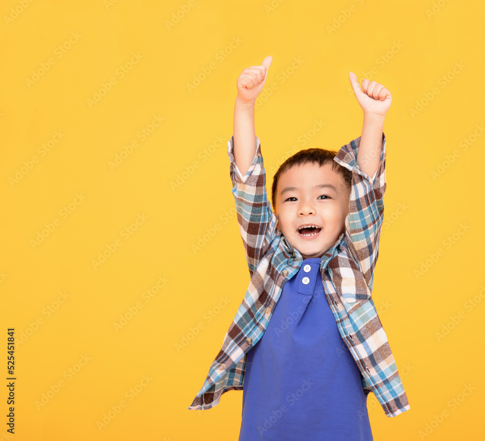 Happy asian boy in front of yellow background and showing thumbs up Happy asian boy in front of yellow background and showing thumbs up