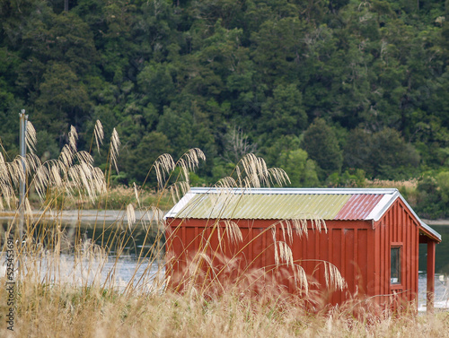 Red trampers hut in New Zealand bush beside river photo