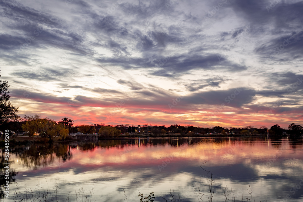 Dramatic pink and purple sunset clouds reflection on Woodlawn Lake San Antonio Texas
